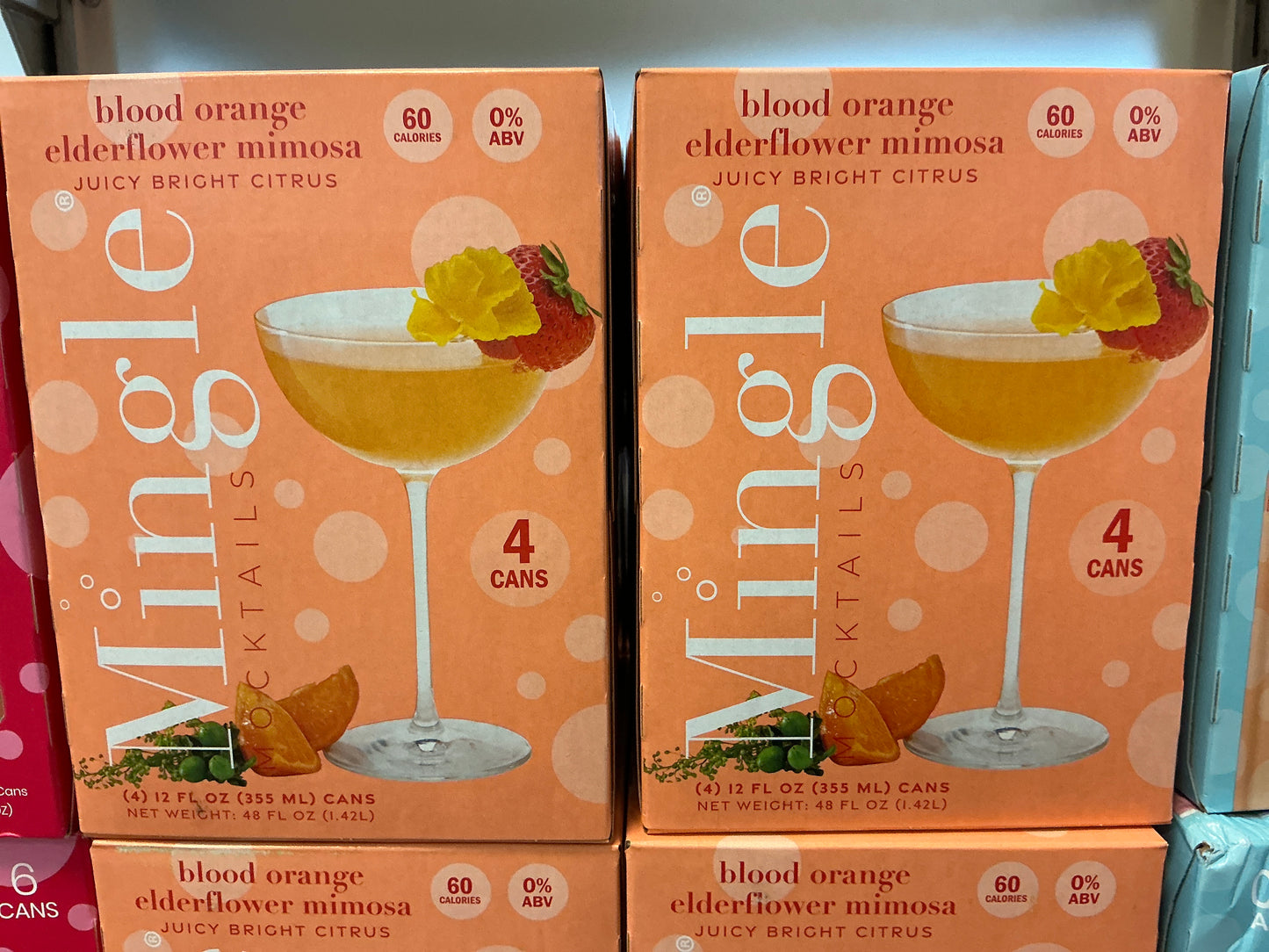 Two boxes of Mingle cocktails labeled 'blood orange elderflower mimosa' on a shelf.