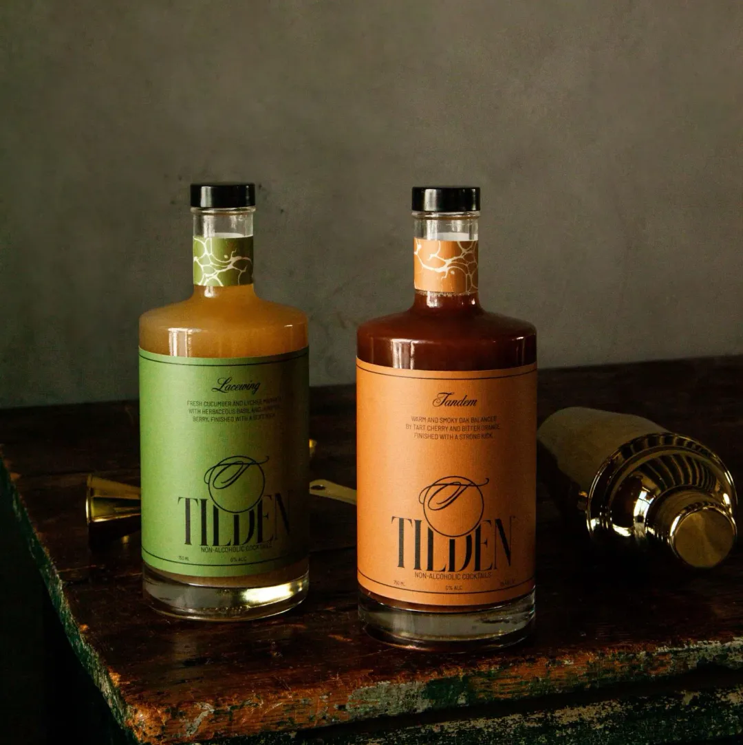 Two bottles of Tilden liquor on a wooden surface with a dark background