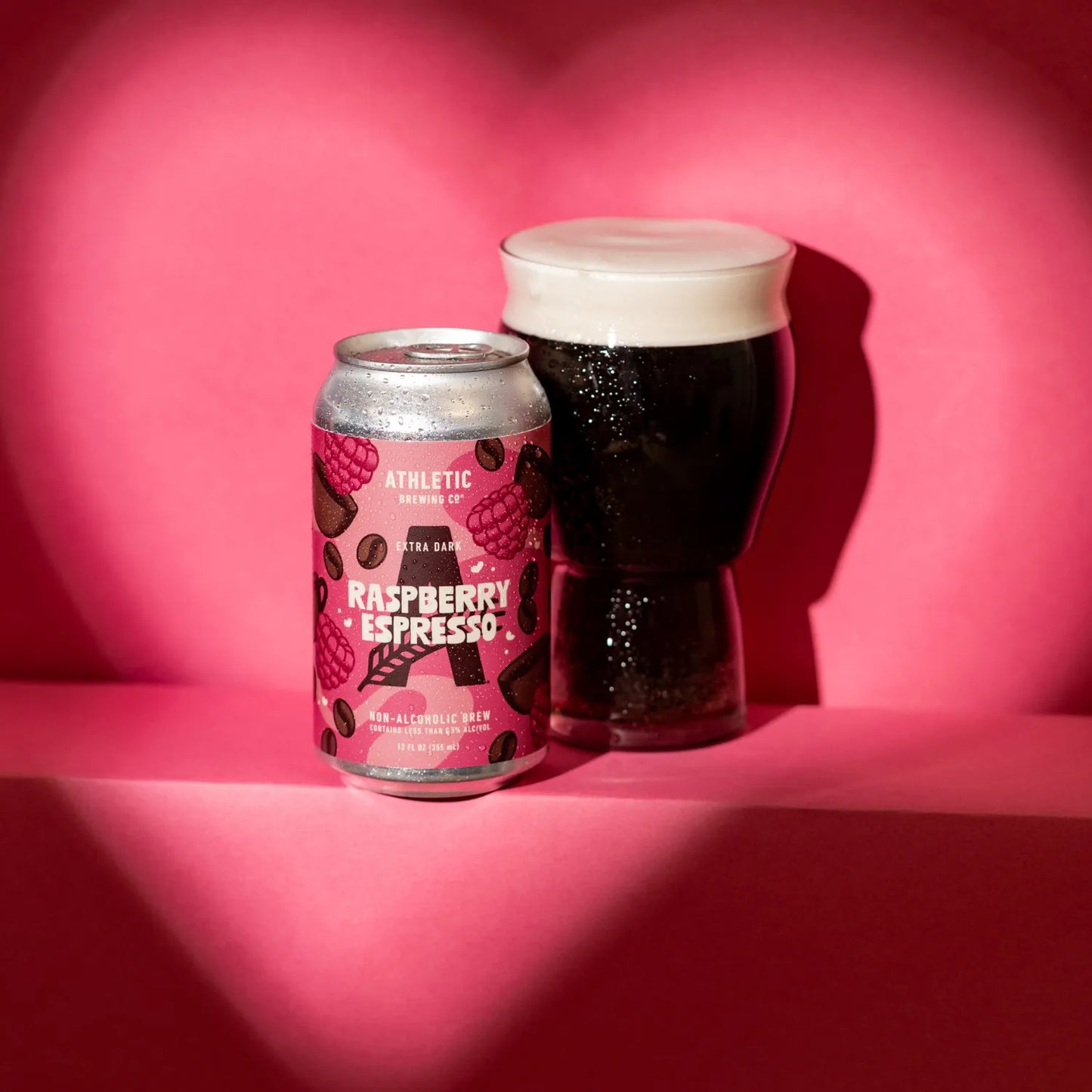 Cans and glass of Raspberry Espresso NA beer on a pink background