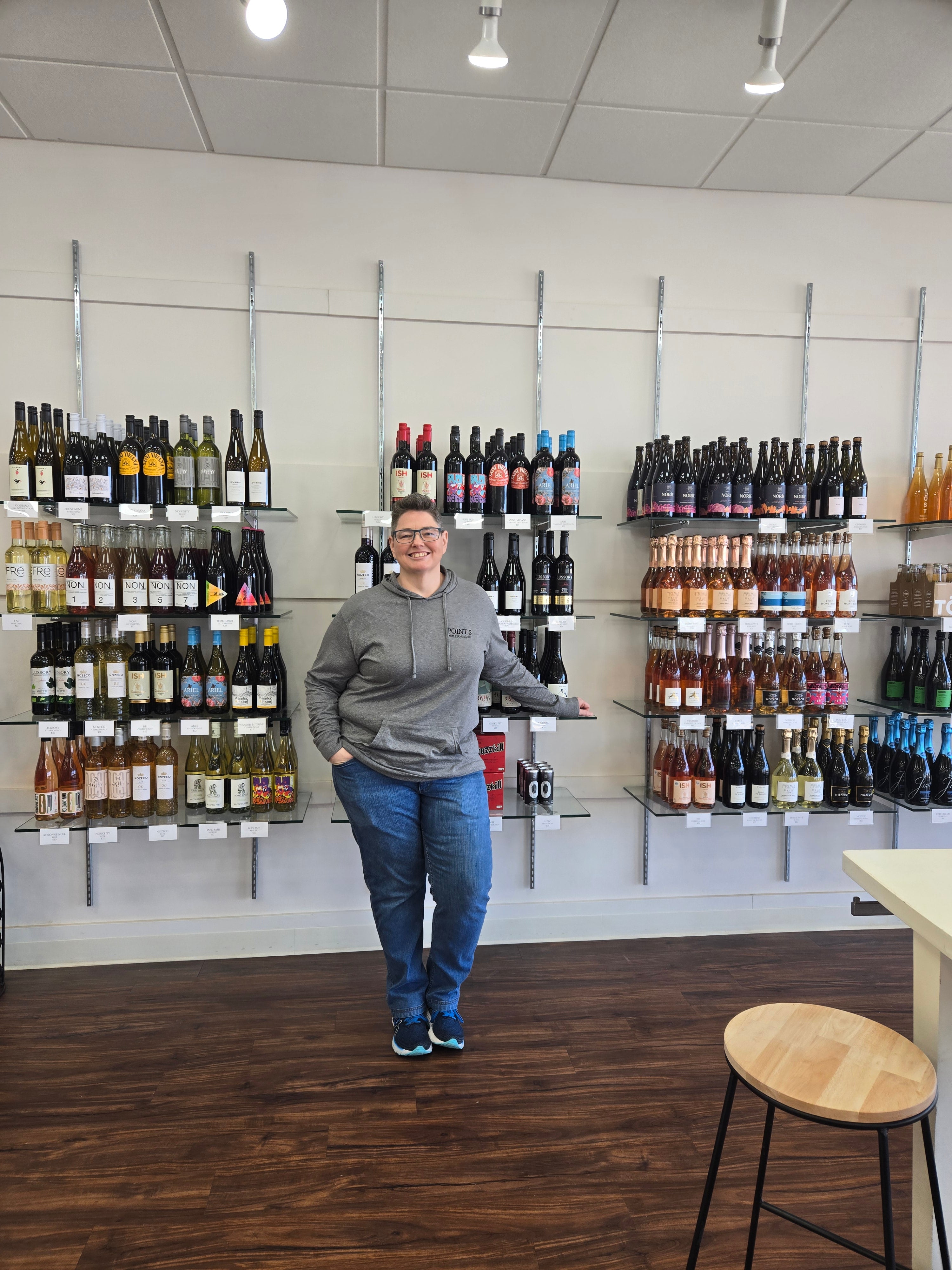 Person standing in a wine store with shelves of bottles.
