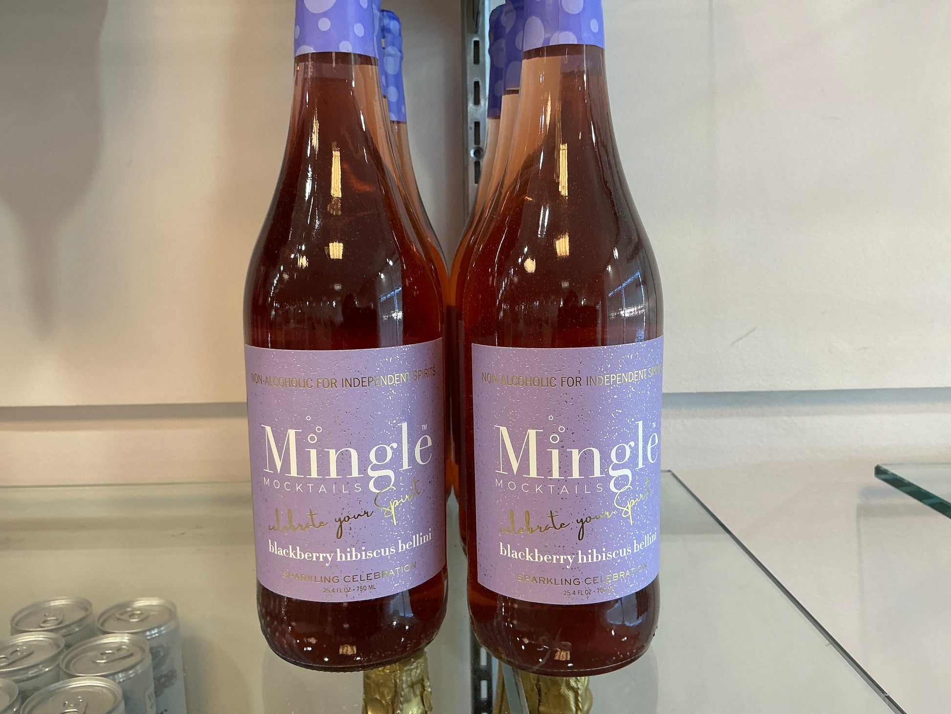 Two bottles of Mingle on a reflective surface with a neutral background