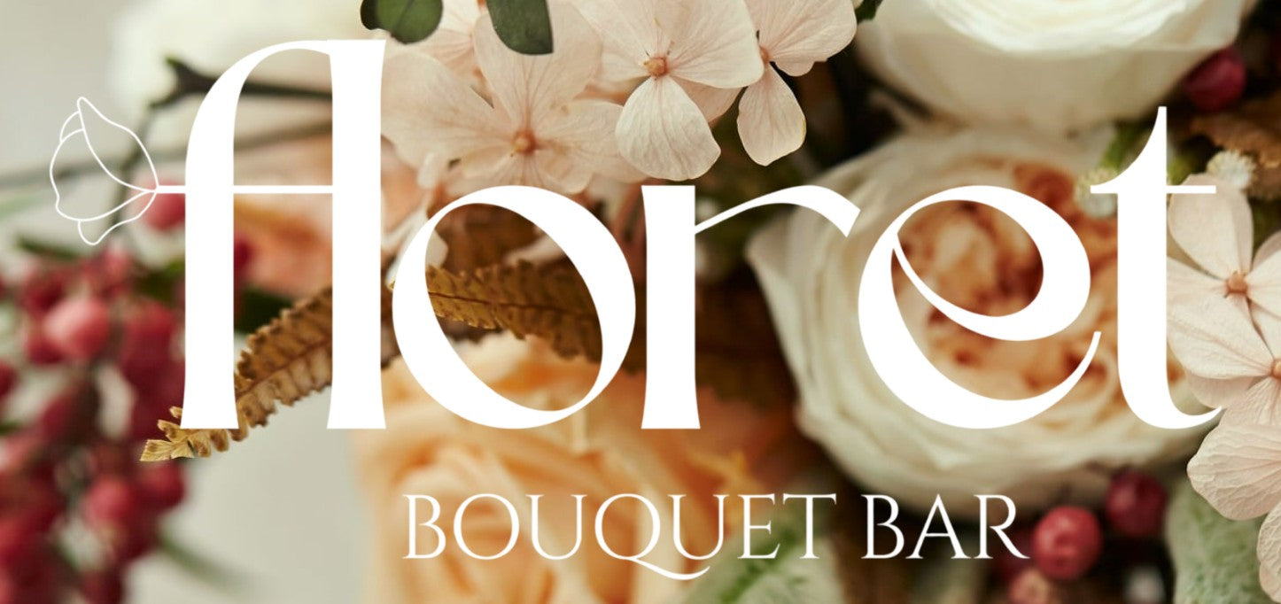 A close-up floral arrangement with large white overlaid text reading 'floret' and smaller text 'BOUQUET BAR'. The bouquet includes pale pink and cream flowers, green leaves, and small red berries.