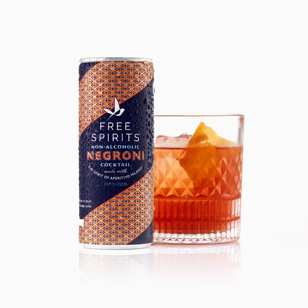 Free Spirits non-alcoholic Negroni cocktail can next to a glass of the cocktail on a white background