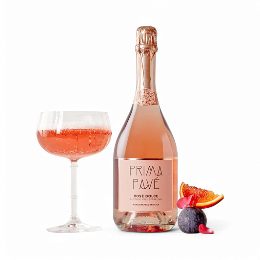 Bottle of Prima Pave Rose Dolce with a glass of pink wine and fruit on a white background