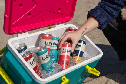 Person reaching into a cooler filled with ice and LUBA beer cans.