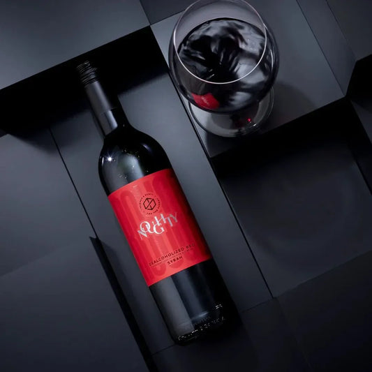 Wine bottle with red label and glass on a dark surface