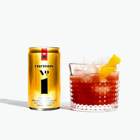 Gold can labeled 'Curious 1' next to a cocktail with ice and a pineapple wedge on a white background