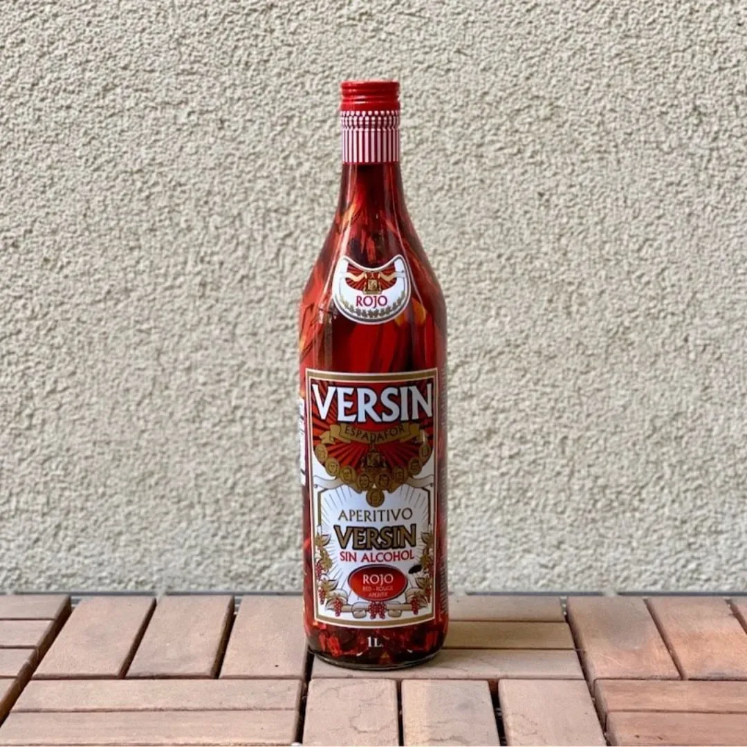 Bottle of Versin Aperitivo on a wooden surface with a light gray background