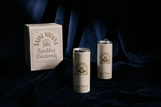 Saint Viviana sparkling wine packaging including a box and two cans on a dark fabric background