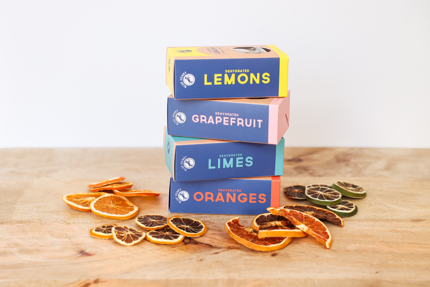 Stack of dried citrus fruit boxes with oranges, lemons, and grapefruit on a wooden surface.