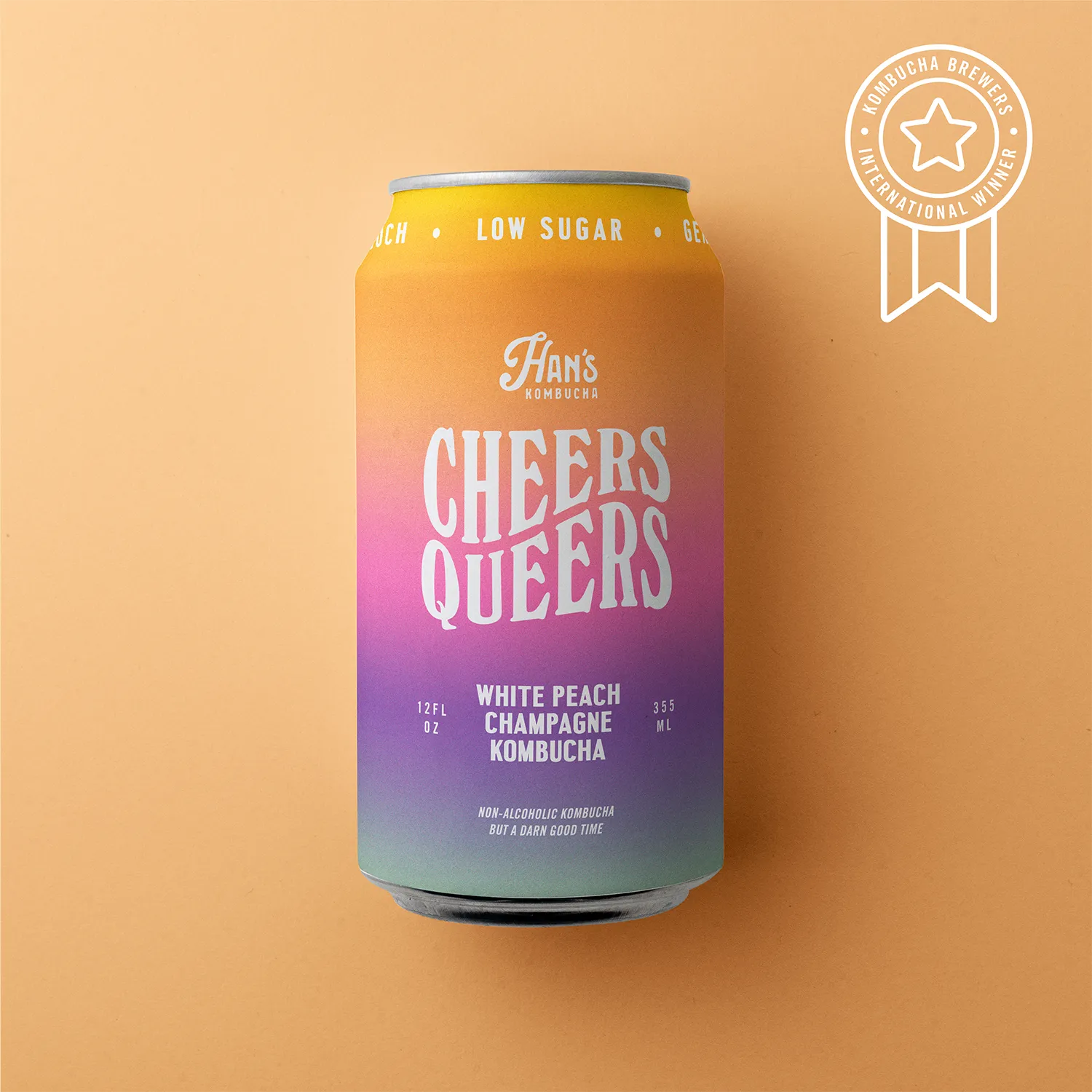 Can of 'Cheers Queers' White Peach Champagne Kombucha with colorful gradient label on a beige background