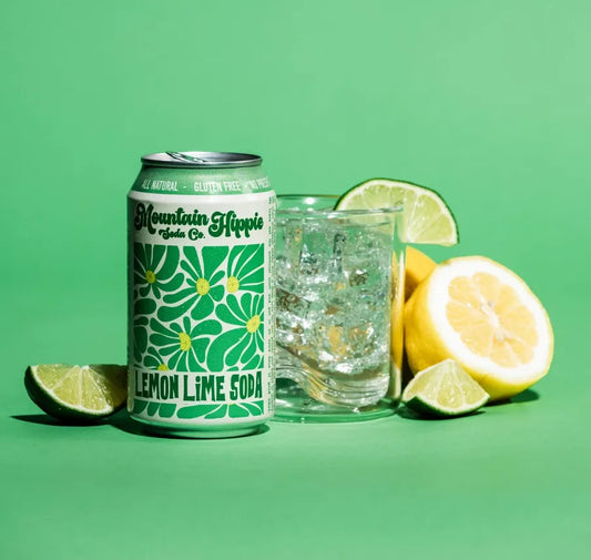 Can of Mountain Hippie Lemon Lime Soda with a glass and lemons on a green background