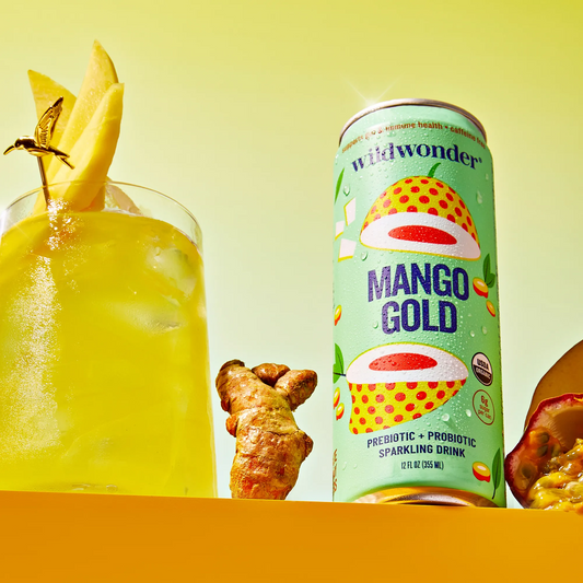 Mango Gold sparkling drink can with a glass of yellow drink and ingredients on a yellow background