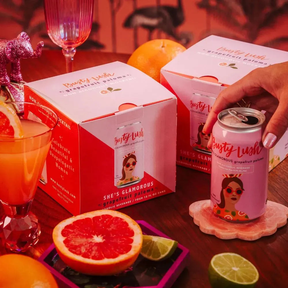 Canned drink with a can opened, half an orange, and a box on a table.