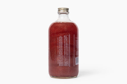 Clear glass bottle with red liquid on a white background