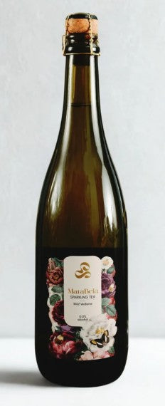 A dark glass bottle of tea with a cork stopper and a floral label, set against a plain light gray background.