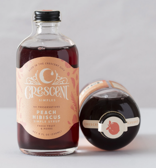 Bottle of Crescent Simples peach hibiscus syrup on a light gray background