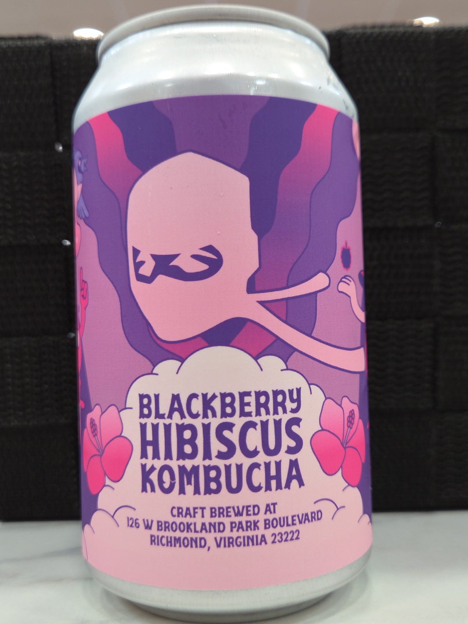 Can of Blackberry Hibiscus Kombucha with a colorful label on a black background