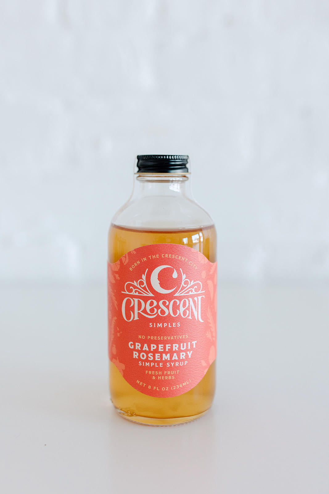 Bottle of crescent simple syrup with a pink label on a white background