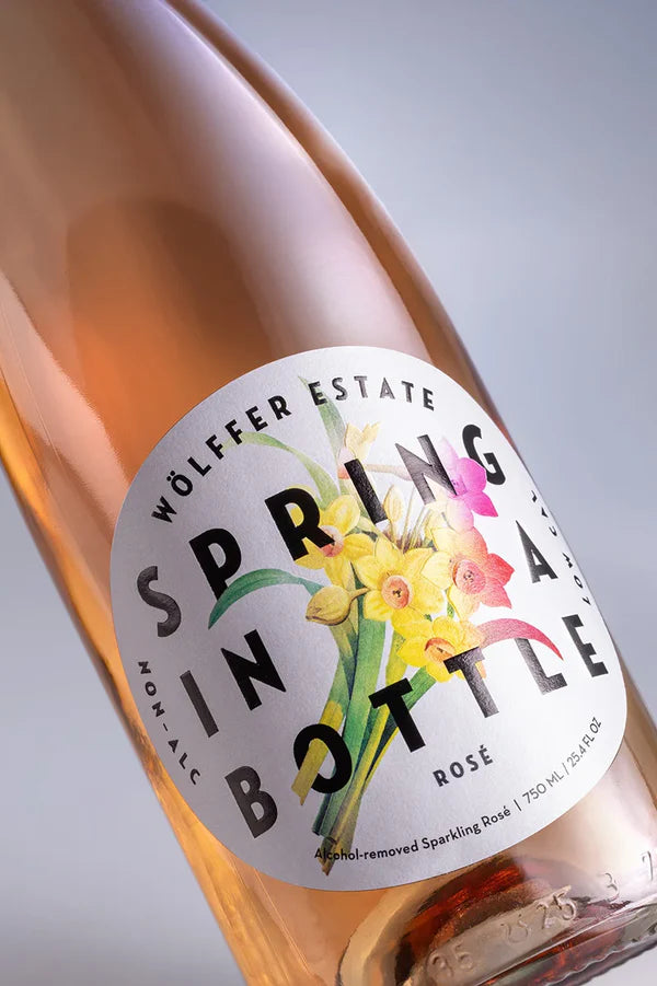 Bottle of Wölffer Estate Spring in a Bottle Rosé with floral label on a light gray background
